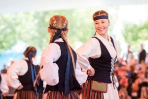 Kaksi kansantanssijaa kyljet kohti toisiaan, taustalla yleisö.
