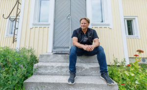 Juha Vidgrén istumassa kotitalonsa portailla.