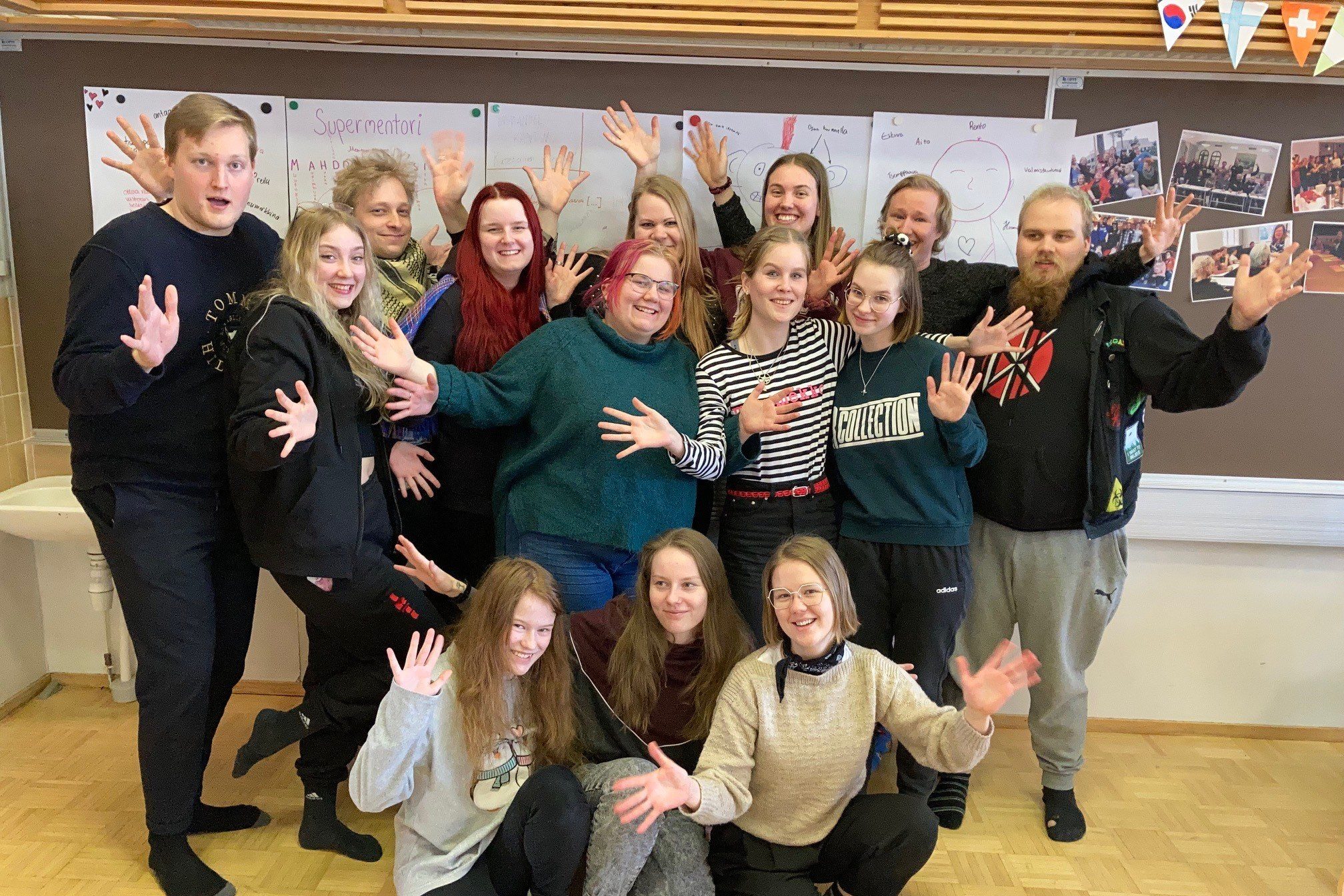Joukko nuoria seisoo yhdessä kädet levitettynä.